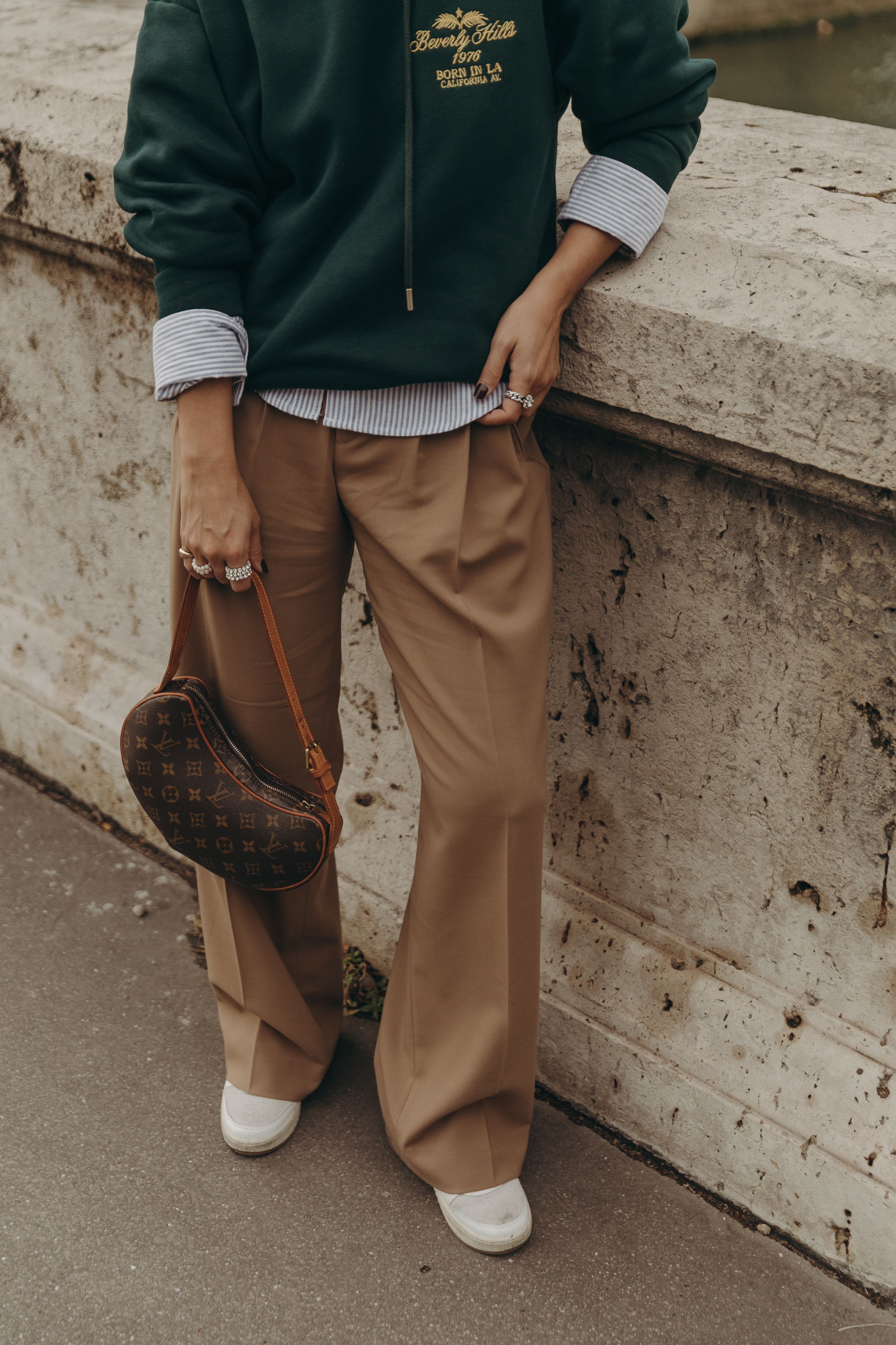 Sara from Collage Vintage at Paris Fashion Week wearing a oversize green sweatshirt, camel trousers, Louis Vuitton vintage bag and sneakers.